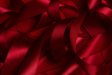 Red textured background of twisted satin ribbon, abstract pattern