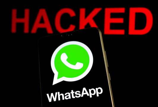 Stone, Staffordshire / UK - October 29, 2019: WhatsApp logo on the smartphone screen in a dark room and the word "Hacked" at the blurred background. Selective focus.