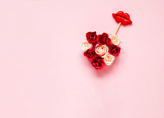 Creative layout with rosebuds and with lips on stick. Valentine day concept or World Kiss Day. Festive pink background.