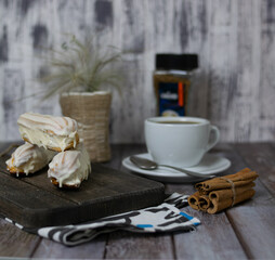 Custard cakes on a dark Board. Black coffee with cinnamon in a white Cup