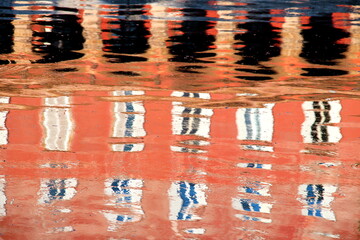 Abstract - reflection on the water of the facade of a red building with its windows