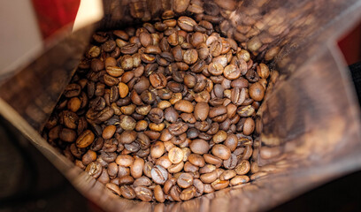 Roasted coffee beans that are filled in a craft bag are shiny inside.