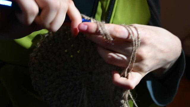 Crocheting as a hobby. A young girl creates with a crochet hook and twine.