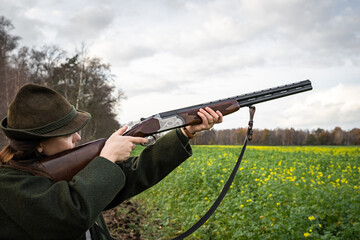Fototapeta premium Jagd und Wildhege - junge Jägerin zielt auf flüchtiges Wild, jagdliches Symbolfoto.