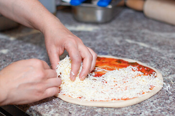 Close-up of hands making pizza