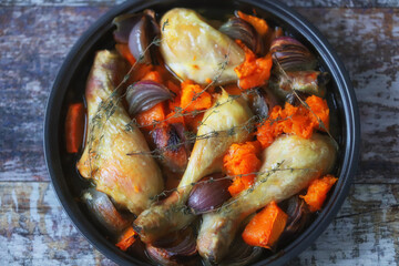 Chicken legs baked with pumpkin and blue onions in a pan. Delicious healthy lunch.