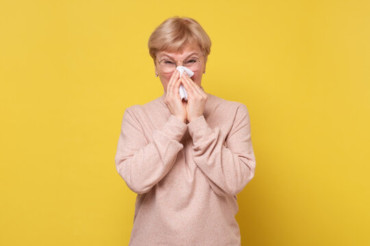 Portrait Of An Attractive Woman Sneezing While Standing Against A White Background