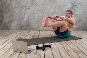funny fat man in sports clothes doing exercises. He plays sports remotely while looking at his...