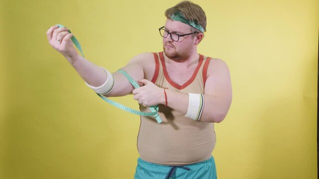 Funny fat man in sportswear measures his hand with centime