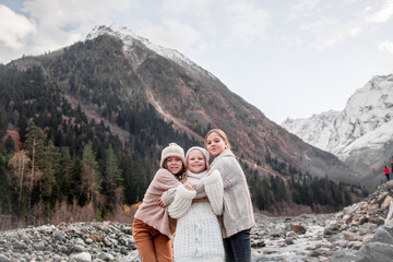 Obraz premium Group of kids hugging and walking outdoor in the nature against the river and beautiful mountains in snow, alpine view