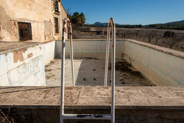 Abandoned empty swimming pool with a rusty ladder