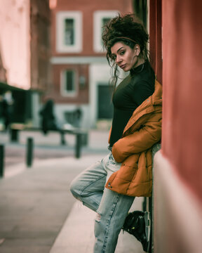 A shallow focus shot of an attractive Latina with an orange down jacket posing at camera