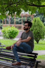 Fototapeta premium man with beard and glasses sitting on bench in park