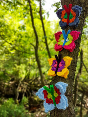 Fake coloful butterflies on a tree in forest.