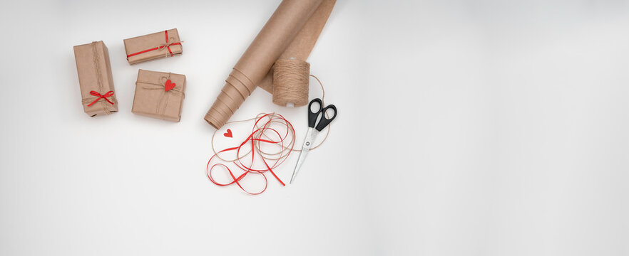 DIY gift wrapping craft paper, red ribbon, twine, scissors. 3 wrapped gifts, on a white background for valentine's day. flatly banner for business