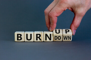 Burn up, not burn down. Male hand flips a wooden cube and changes words 'burn down' to 'burn up'. Beautiful grey background, copy space. Business, psychological and burn up or burn down concept.