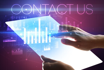 Hand holding futuristic tablet with CONTACT US inscription above, modern business concept