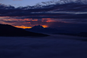 Sundown over the clouds with Swiss mountains in background. Copy Space.
