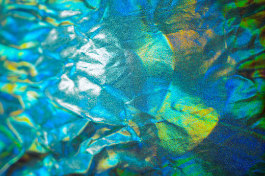 Iridescent fabric holographic background. Crumpled surface in blue foil