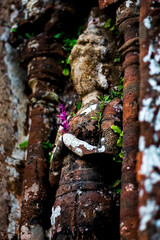Statue holding flower in arms hands, Vietnam My Son Buddhist temple 