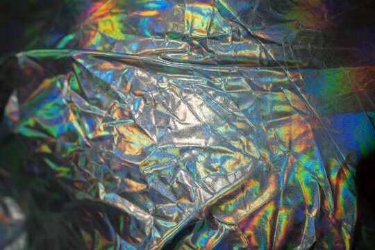 Iridescent fabric trendy cloth holographic background. Colorful chrome fabric. © Alex