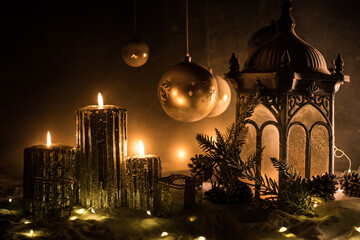 Creative artwork decoration. Christmas decoration with burning candles on a dark background. Christmas ornaments over dark golden background with lights.