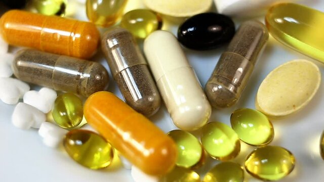 White, yellow, brown, transparent, black, oval and oblong tablets, pills, capsules, water and fat-soluble smoothly move in the frame from right to left. Close-up, real time, on a white background