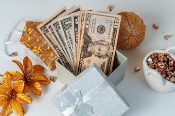 dollar bills in a gift box as a christmas present next to christmas accessories and a protective face mask
