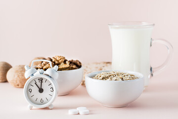Good sleep. Foods for good sleep - milk, walnuts,  oatmeal, sleping pill and alarm clock on pink background