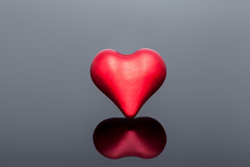 volumetric symbol of a heart of red on a black background with reflection, a symbol of health and love on the medical theme of celebrating Valentine's Day.