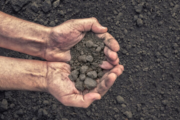 Dirty male hands holding dark moist soil. Agriculture, organic gardening, planting or ecology concept. Environmental, earth day, Top view