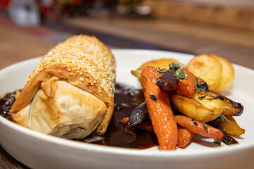 A delicious plate of Jackfruit, stage and Onion strudel on a wooden restaurant table
