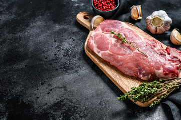 Raw marble pork steak on a wooden chopping Board. Organic meat. Black background. Top view. Copy space