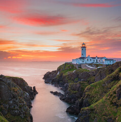 white lighthouse on the coast at sunset in Ireland