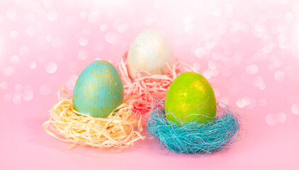 Three Easter eggs in a nest on a pink background.