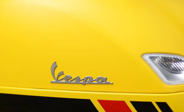 BRUGES, BELGIUM - OCTOBER 5, 2019: Detail of yellow Vespa scooter with black and red accents. The brand was released in 1946 in Rome by Piaggio and is a popular means of transport in urban environment