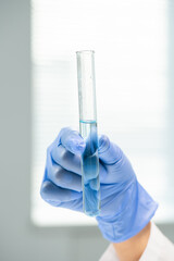 Gloved hand of contemporary young researcher holding flask with pure water