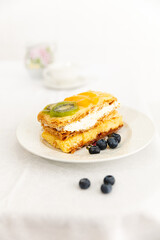 Cream and cream dessert with fruits. Kiwi, peach and blueberries.