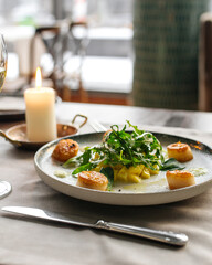 Gourmet cooked and garnished scallops on the served restaurant table