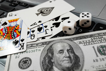 dice, playing cards on laptop keyboard dollars and euro bills