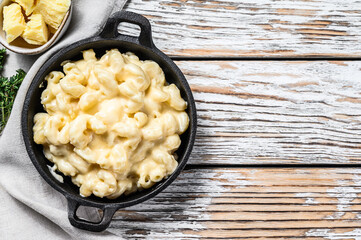 Mac and cheese, american style macaroni pasta in cheesy sauce.  White wooden background. Top view....