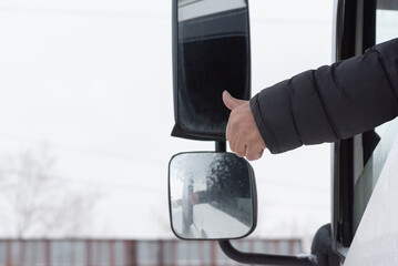 Truck driver is showing a thumbs up gesture close up. Best transportation service.