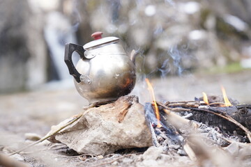 Steaming Hot Kettle on Flaming Log Firewood Campfire. Close up