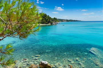 Beautiful bay with beach Aegean Sea on Chalkidiki, Greece, azure blue water under sky with clouds, vacation destination