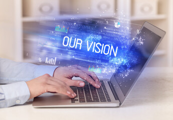 Closeup of businessman hands working on laptop with OUR VISION inscription, succesfull business concept