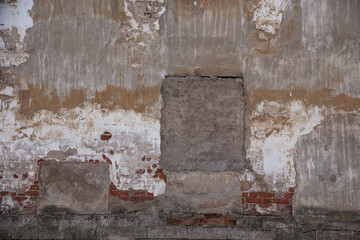 fragment of an old brick wall with concrete plaster and remnants of multicolored paint, grunge, background