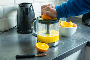 Person is making juice from fresh oranges with and electric squeezer or juicer 