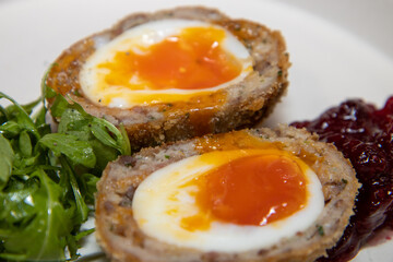 A delicious home made scotch egg on a white plate with salad