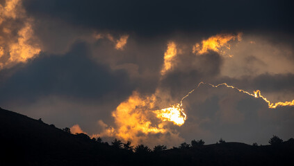 Sunset with stormy cloud sky and hidden sun behind the clouds