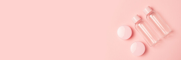Empty tubes for cosmetics on a pastel pink background. Flat lay, top view. Banner